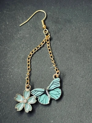 By prisförslag- 1 st örhänge Turkos med blommigt och fjärilsmotiv - Snyggt örhänge med turkos blomma och fjärilsmotiv, perfekt för dig som vill sticka ut. Den har en cool design med detaljer i guld och turkos. 
