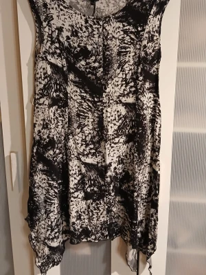 Svartvit mönstrad klänning KappAhl - Säljer en svartvit klänning från KappAhl i storlek 36/38. Klänningen har ett abstrakt mönster, är ärmlös och har asymmetrisk nederkant med lätt transparent tyg. Perfekt för dig som gillar unika detaljer och sköna material.