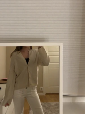 Beige kofta från H&M - Mysig beige kofta från H&M i storlek XS. Koftan har en avslappnad passform, långa ärmar och knappar framtill. Perfekt att slänga över en topp för en enkel och clean look.