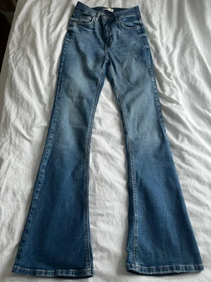 Blå bootcut jeans från Gina Tricot - Säljer ett par blå bootcut jeans från Gina Tricot, modell Perfect Jeans. Snyggt utsvängda ben och stilren tvättad look. Perfekta för dig som gillar retrovibbar och bekväm passform.