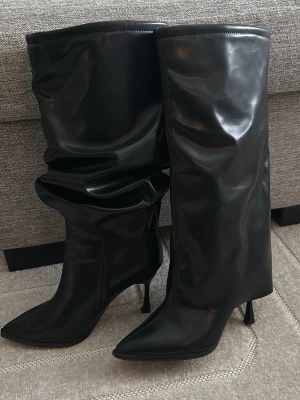 Svarta högklackade stövlar – stilrena & eleganta - Snygga svarta stövlar med klack och spetsig tå. Elegant och stilren modell i syntetläder/konstläder. Mjukt skaft med naturligt fall som ger en trendig look. Använda fåtal gånger och i mycket fint skick, utan skador.