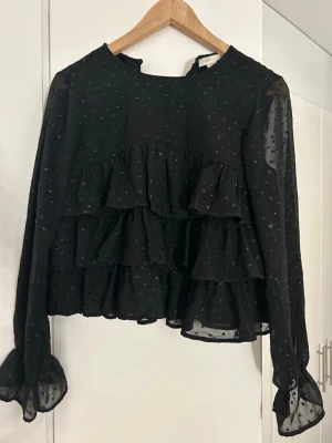 Söt blus från Gina  - Söt blus med volang och små glittrande detaljer! Passar perfekt till kostym byxor och jeans. Endast använt 1-3 gånger.