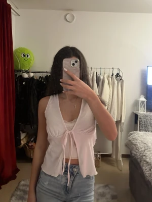 Ljusbeige omlottopp med knyt - Säljer en ljusbeige omlottopp från 1517. Toppen är ärmlös, har v-ringning och knyt framtill. Materialet är ribbat och lätt, vilket ger en luftig känsla. Perfekt att styla med jeans eller kjol för en fräsch look.