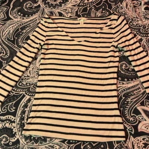 Randig långärmad topp från H&M - Säljer en vit och svart randig långärmad topp från H&M i storlek S. Toppen har v-ringad hals och är tillverkad i mjuk, ribbad bomull. Perfekt för dig som gillar klassiska mönster och enkel stil.