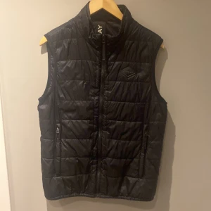 Väst - Snygg svart dunväst från Replay med quiltad design. Västen har dragkedja framtill och två sidofickor med dragkedja. Perfekt att slänga över en hoodie för extra värme. Pris kan diskuteras 