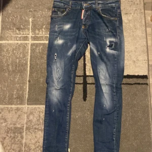 Blå Dsquared2 Skater Jeans - Säljer ett par blå Dsquared2 Skater Jeans med slitna detaljer och coola tvättade effekter. Jeansen har klassisk femficksdesign, smal passform och orange sömmar. Perfekt för dig som gillar streetstyle och vill sticka ut med snygga jeans. Säljer för 600 men pris kan diskuteras.