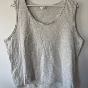 Grå ribbad linnetopp XXL - Säljer en enkel och chill grå linnetopp i storlek XXL. Toppen är ribbad och har en rundad halsringning samt ärmlös design. Perfekt för varma dagar eller som layering-piece. Materialet känns mjukt och skönt mot huden.