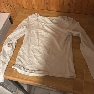 Ljusbeige långärmad topp från 157 - Ljusbeige långärmad topp från 157 med rund halsringning. Enkel och stilren design i mjukt bomullsmaterial, perfekt för att bygga lager eller bära som den är. Passar dig som gillar basic och clean look.