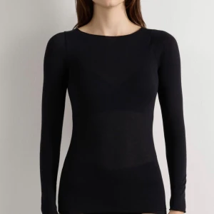Svart långärmad intimissimi - Slimmad svart långärmad topp i mjuk och tunn merinoull. Rund halsringning och enkel design utan synliga detaljer eller mönster. Perfekt att styla lager på lager eller som den är för en clean look. 