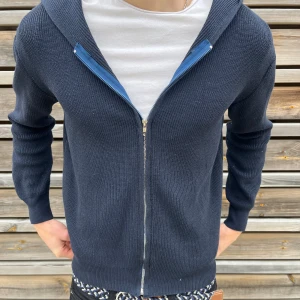  stickad hoodie med dragkedja - Säljer en riktigt snygg mörkblå stickad hoodie. kommer tyvärr inte ihåg vad det är för märke. modellen är 178 och bär modellen S. den är liten i storleken så rekommenderar den inte om du är runt min längd.
