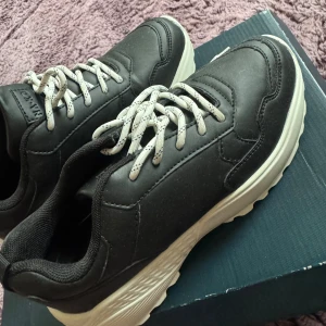 Svarta chunky sneakers från NA-KD, helt nya. - Chunky svarta sneakers från NA-KD med vit, mönstrad snörning och tjock vit sula. Ovandelen är i syntetmaterial med snygga paneldetaljer och rund tå. Insidan är mjukt fodrad för extra komfort. Perfekt för dig som gillar streetstyle och vill ha en cool look.