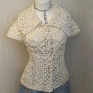 Virkad/stickad Cremevit topp kofta - Det förekommer noppor på olika ställen. Är i relativt bra skick , men fortfarande inte fantastiskt . Står S/M på lappen men jag uppskattar storleken till M/L/XL, men eftersom jag inte är någon av dessa storlekar kan man referera till måtten: midja tvärs över när koftan  är stängd = 45cm. Ärm till ärm: 60 cm. 100% akryl. Toppen är stretchig.