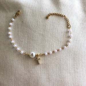 Pärlarmband med bokstav och kors - Fint armband med små vita pärlor på guldfärgad kedja. I mitten sitter en rund vit pärla med bokstaven A i guld och ett litet kors i diamanter som glittrar. Jättefin men kommer inte t användning (Inte äkta silver!)