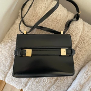 Svart axelväska från H&M med gulddetaljer - Väska från H&M, använd 2-3 gånger 