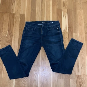 Replay Anbass mörkblå jeans - Snygga mörkblå Replay Anbass jeans med klassisk femficksdesign och diskreta slitningar. Jeansen har raka ben, normal passform och är tillverkade i mjukt denimtyg med stretch för extra komfort. Perfekta för dig som gillar stilrena och moderna jeans.
