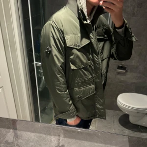 Olivgrön field jacket från J.Lindeberg  - Säljer en olivgrön field jacket från J.Lindeberg med fyra stora fickor framtill, hög krage och dragkedja. Jag är 188cm och bär storlek M vilket passar ganska bra. Nypris ligger strax under 3500kr. Pris kan alltid diskuteras. En liten defekt, knappen är sprucken på en knapp men inget man märker. Hör av er vid frågor;)