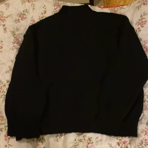Svart stickad polotröja från SHEIN - En svart stickad polotröja från SHEIN i storlek S. Tröjan har en hög krage och långa ärmar med ribbade muddar. Perfekt för kyligare dagar och enkel att matcha med olika outfits.