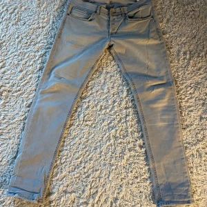 Dondup jeans (grå) - Snygga ljusgrå dondup jeans med smal passform och klassisk femficksdesign. Jeansen har en lagad detalj på låret och en liten slitning på bakfickan.