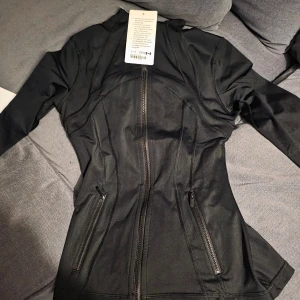 Svart träningsjacka från Lululemon - Säljer svart luluemon define i nytt skick som är köpt här på Plick. Råkade köpa två likadana därav säljer jag en. Säljer för samma pris som jag köpte den för! Storlek 4 