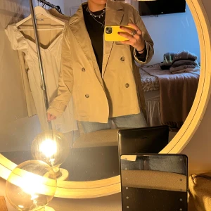 Beige trenchcoat med bälte och knappar - Säljer denna supersnygga oversized beigea trenchcoaten med dubbelknäppning och bälte i midjan. Helt ny med prislappen kvar!!!🤎🤎🤎