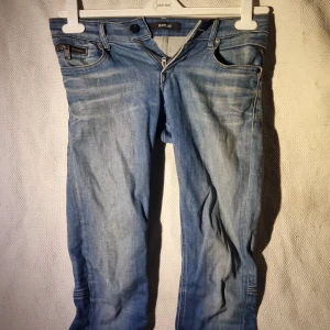 Blå jeans från Replay, midja 25/30 - Snygga blå jeans från Replay med klassisk femficksdesign, dragkedja och knapp framtill. Jeansen har ljus tvätt och diskreta slitningar på bakfickorna. Modellen är rak och passar perfekt till en avslappnad stil.