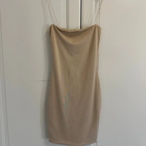 Beige bodycon klänning från Meshki - Snygg beige bodycon klänning från Meshki med tunna axelband och draperad halsringning. Klänningen är kort och har en smickrande tight passform samt dragkedja bak. Perfekt för dig som gillar minimalistisk och stilren look.