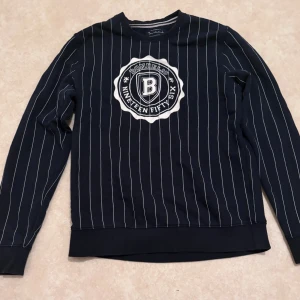 Randig tröja från Bondelid marinblå - Snygg marinblå tröja från Bondelid med vita tunna ränder och stort tryck på bröstet. Klassisk rund halsringning och långa ärmar. Perfekt för dig som gillar sportig och stilren look. Priset går alltid att diskutera. Hör av er om ni undrar något!😊