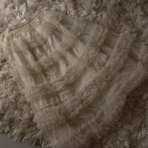 Champagnefärgad volangklänning Lissimo - Lissimos drömlika kjolklänning i vitt meshtyg med flera lager volanger. Kjolen har en luftig och romantisk känsla tack vare det genomskinliga tyget och den resåriga midjan. Perfekt för dig som vill sticka ut från mängden med en verkligt unik stil.