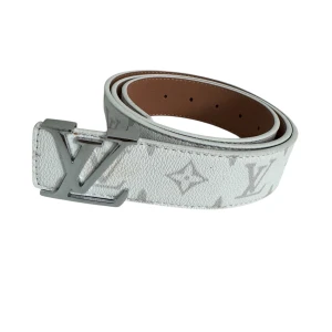 Vit Louis Vuitton skärp med monogram - Säljer ett snyggt vitt Louis Vuitton bälte med klassiskt monogrammönster och en stor LV-spänne i silver. Bältet är tillverkat i skinn och har en bred, rak form med bruna insidor. Perfekt för dig som vill ha en lyxig och stilren accessoar.