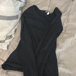 Svart långärmad klänning H&M XS - En enkel svart långärmad klänning från H&M i storlek XS. Klänningen har rund halsringning och är figurnära i modellen. Perfekt basplagg som funkar till många olika stilar.