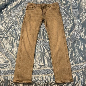 Levis 511 ljusgrå jeans W29 L32 - Säljer ett par Levis 511 jeans i ljusgrå tvätt med klassisk femficksdesign och smal passform. Jeansen har normal midja, raka ben och är tillverkade i mjukt jeanstyg med snygga detaljer som Levis-lappen bak och röd etikett på fickan.