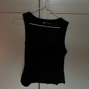 Svart linnetopp från Zara - Snygg svart linnetopp från Zara med breda axelband och fyrkantig halsringning. Toppen är figurnära och har en stilren, minimalistisk look. 🌟