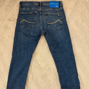 Jacob Cohën blå jeans Type 688C - Snygga blå jeans från Jacob Cohën, modell Type 688C. Klassisk femficksdesign med gul kontrastsöm och en blå patch med metallogo bak. Jeansen har straight passform och är tillverkade i mjukt bomullstyg med dragkedja och knappstängning framtill. Jeansen är i längd 32. Pris går absolut att diskutera vid snabb affär.