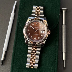 Seikmod Datejust brun/silver/guld klocka - Snygg Seikmod Datejust med brun urtavla och glittrande index. Klockan har tvåfärgad länk i silver och guldton, samt räfflad bezel. Urtavlan har datumfönster och eleganta visare. Perfekt accessoar för dig som gillar stilren design med lyxig känsla.