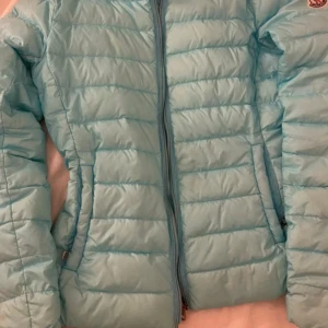 Ljusblå Moncler dunjacka - Säljer en sjukt snygg ljusblå dunjacka från Moncler med klassisk logga på ärmen och coolt serietryck på insidan. Jackan har dragkedja framtill och är quiltad för extra värme. Perfekt för dig som vill ha en stilren och trendig vinterjacka. Är lite smutsig på vissa ställen men annars jättebra skick. Stolek 2 som motsvarar M, men skulle säga att den passar som S också