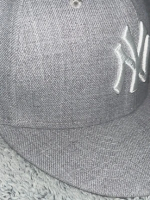 Grå New York Yankees keps - helt ny aldrig använd! Snygg grå keps från New Era med New York Yankees-logga broderad framtill i vitt. Klassisk flat brim och strukturerad passform. Tillverkad i ett tåligt tyg med diskreta sömmar och MLB-logga broderad baktill. priset ej hugget i ste 