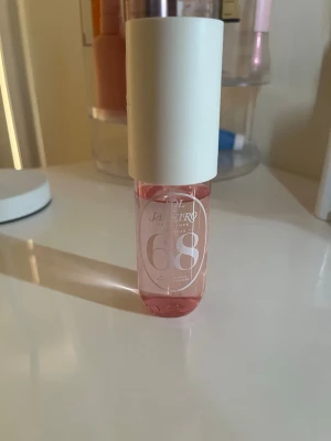 Sol de Janeiro 68 parfym mist - Fräsch parfym mist från Sol de Janeiro i doften 68. Flaskan är cylinderformad med rosa genomskinligt glas och ett stort vitt lock. Perfekt för dig som gillar söta och blommiga dofter.