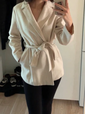 Beige kappa med knytskärp - Stilren beige kappa. Passar perfekt nu till hösten. 