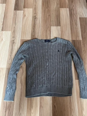 Grå kabelstickad tröja Polo Ralph Lauren för barn 11-12 år. - Klassisk grå kabelstickad tröja från Polo Ralph Lauren. Den är i mycket bra skick och passar för barn i 11-12 års åldern😊om ni har några frågor är det bara att skriva😁