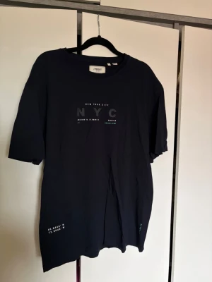 Svart NYC t-shirt  - Snygg svart t-shirt från Produkt med trycket 'NYC' på bröstet och små vita detaljer. 