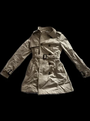 Trench coat - Jätte snygg trenchcoat från cubus. Skulle säga att den passar storlek S och M. Snyggt bälte som gör att den sitter mer figursytt.