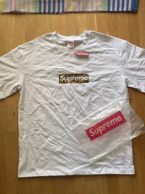 Supreme t shirt - Tja! Jag säljer en snygg Supreme t-shirt i vitt med klassisk box logo framtill i leopardmönster. T-shirten har korta ärmar och är gjord i mjuk bomull. Perfekt för dig som vill sticka ut med streetwear-vibe.