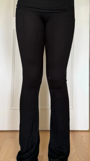 Svarta yogapants - Säljer ett par svarta leggings med bootcut-modell och låg midja. De är stretchiga och sitter tight upptill men har utsvängda ben nertill. Perfekta för en avslappnad och trendig look. Materialet känns mjukt och bekvämt mot huden.