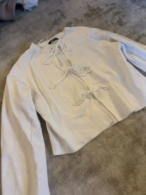 Vit stickad tröja med knyt från Gina Tricot - vit stickad tröja från Gina Tricot med tre knytband . Tröjan har lång ärm, ribbad halsringning och är gjord i mjukt stickat.💕