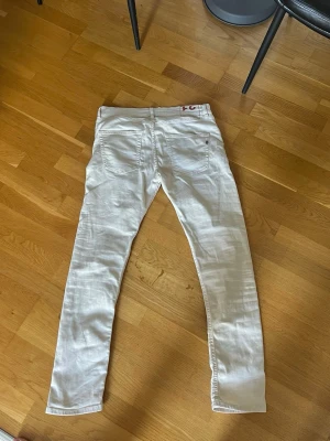 DonDup slim fit jeans - Säljer ett par vita (ljusbeige) slim fit jeans med klassisk femficksdesign och smal passform. Jeansen har normal midja och raka ben. Perfekta för dig som vill ha en clean och stilren look. Materialet ser ut att vara bomull med lite stretch.