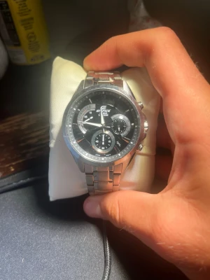 Casio Edifice kronografklocka silver - Stilren Casio Edifice kronografklocka i silver med svart urtavla och flera små urtavlor. Nypris 1899kr. Klockan fungerar när annonsen läggs upp och har Casios berömda 10års batteri. Full set (Box, kudde, papper) medföljer