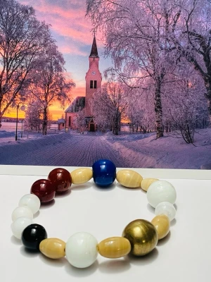 Färgglatt pärlarmband i olika toner - Snyggt armband med stora pärlor i flera färger som blått, rött, vitt, svart, guld och beige. Pärlorna är runda och ovala och sitter på en elastisk tråd. Perfekt accessoar för dig som gillar färg och vill sticka ut lite extra.