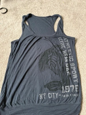 Mörkblå linnetopp med tryck - Snygg mörkblå linnetopp med sportigt tryck på framsidan där det står 'ATHLETIC SPORT', 'NY CITY' och '1978'.  Vintage linnetopp🔥 vet tyvärr inte vart den är ifrån men älskar 