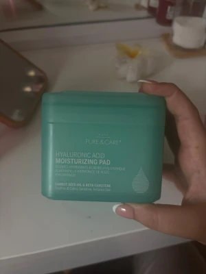 Hyaluronic Acid Moisturizing Pad - Fuktgivande toner pads från Pure & Care med hyaluronsyra, morotsfröolja och betakaroten. Kommer i en mintgrön fyrkantig plastburk med lock. Padsen är vita och runda, perfekta för att lugna och återfukta känslig hud.