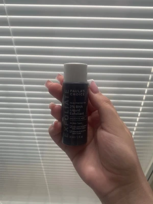 Paula's Choice 2% BHA Liquid Exfoliant - En liten flaska med Paula's Choice 2% BHA Liquid Exfoliant. Tonern är i en mörkgrå plastflaska med vit skruvkork och text i vitt. Innehåller salicylsyra och passar alla hudtyper. Perfekt för exfoliering och att få en klarare hud. Den håller dig länge då man inte använder mycket produkt.